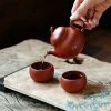 Pouring tea from a Yixing Clay Gongfu Tea Set teapot into a teacup, demonstrating the traditional gongfu tea brewing process with a Yixing Gongfu Tea Set