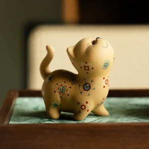 Yixing Cat tea pet on a wooden tea tray, a decorative cat tea pet with vintage floral patterns, styled in a cozy tea room setting to highlight its aesthetic appeal