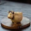 Golden clay Yixing Sheep Tea Pet with intricate carved wool details, placed on a wooden disc to highlight its cute, playful design for tea lovers