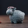 Blue clay Yixing Sheep Tea Pet with a textured wool design, paired with a dried flower accent for a charming, natural tea table display