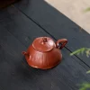 Angled view of a Yixing Lotus Purple Clay Teapot displayed on a dark wooden surface with bamboo accents, emphasizing the artisanal craftsmanship of Yixing Lotus Pottery