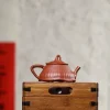 Yixing Lotus Purple Clay Teapot resting on a vintage wooden crate, a premium piece of Yixing Lotus Pottery presented in a minimalist setting for product display