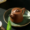 Handmade Yixing Purple Clay Teapot from Yixing Zisha Tea Set resting on a ceramic plate, part of a traditional Yixing Clay Tea Set for Gongfu tea preparation