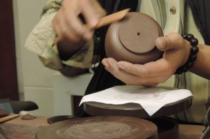 Yixing Teapot Comprehensive Guide: History And Making Methods 2 Artisan refining a Yixing teapot lid, a key step in making a Yixing teapot, ideal for your Yixing teapot guide on traditional craftsmanship and history.