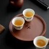 Ceramic teacups placed on the Yixing Zhuni water storage tea tray, creating a peaceful and elegant gongfu tea table scene with the zisha tray