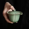 Holding a Celadon Gaiwan with Strainer, featuring a petal-shaped rim and integrated Gaiwan Tea Infuser for effortless brewing.