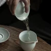 Pouring tea from a Celadon Gaiwan teacup into a fairness pitcher, demonstrating the elegant gongfu tea brewing process with this delicate gaiwan.