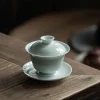 Minimalist Celadon Gaiwan teacup with lid and saucer, showcasing its glossy celadon glaze on a rustic wooden tabletop.