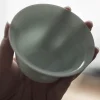 Close-up of a Celadon Gaiwan, held to reveal its smooth, pale green interior glaze, a premium Gaiwan Teacup for tea lovers.