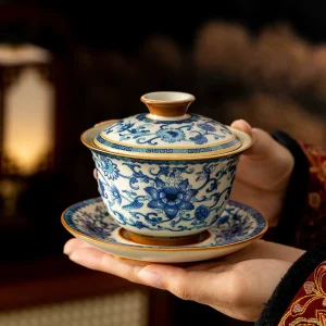 Holding a complete Porcelain Gaiwan Tea Set, featuring a gaiwan, lid, and saucer with traditional blue and white floral motifs.
