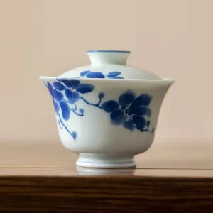 Close-up of a Dehua Gaiwan, showcasing delicate blue and white floral artwork on smooth porcelain material.