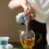 Pouring tea from a Clay Gaiwan into a glass pitcher, demonstrating the functional use of this Dehua Porcelain Gaiwan.