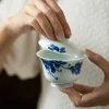 Holding a Dehua Porcelain Gaiwan and lifting its lid, revealing the clean interior of this handcrafted Clay Gaiwan.