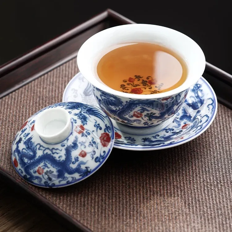 Dragon and Phoenix Auspicious Stoneware Gaiwan 165ml 4 Dragon Gaiwan filled with amber tea, featuring a soft stoneware glaze and hand-painted red floral accents on the porcelain surface.