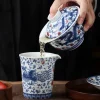 Dragon and Phoenix Auspicious Stoneware Gaiwan 165ml 13 Pouring tea from a Stoneware Gaiwan into a matching pitcher, demonstrating the classic use of this hand-painted Dragon Gaiwan.