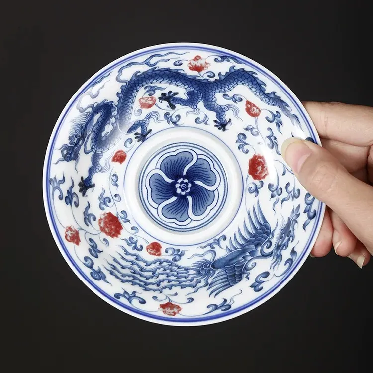 Dragon and Phoenix Auspicious Stoneware Gaiwan 165ml 8 Holding a matching saucer for a Dragon Gaiwan, featuring elaborate blue dragon and phoenix designs on durable Stoneware material.