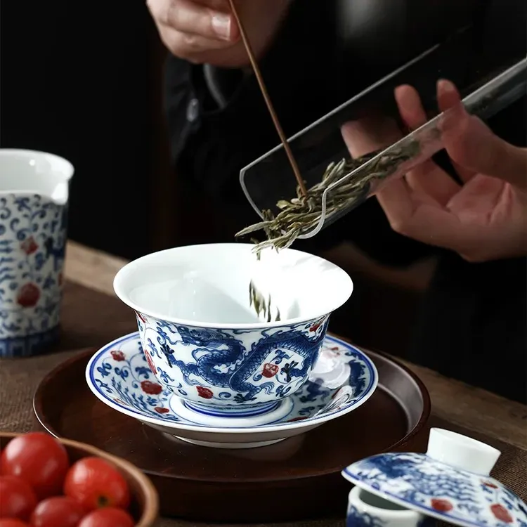 Dragon and Phoenix Auspicious Stoneware Gaiwan 165ml 2 Adding tea leaves to a Stoneware Gaiwan, capturing the traditional tea preparation process with this iconic Dragon Gaiwan.