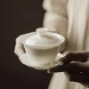 Holding a minimalist White Gaiwan with lid and saucer, showcasing the smooth, luminous finish of Dehua white porcelain.