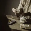 A traditional gongfu tea ceremony featuring a White Porcelain Gaiwan, teacups, and a fairness pitcher on a woven tea mat.