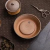 Traditional tea setup featuring an Unglazed Gaiwan, a matching ceramic tray, and tea tools arranged on a dark woven mat