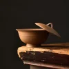 Unglazed Gaiwan with lid partially open, resting on a weathered wooden surface to highlight its rustic, handcrafted design