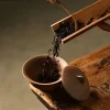 Loose tea leaves being poured into an Unglazed Gaiwan, showcasing the traditional gongfu tea preparation process.