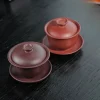 A set of two Gaiwan Handmade from Yixing clay, in deep purple and bright red, displayed on a dark wooden table for elegant tea service.
