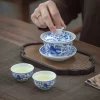 Jingdezhen Porcelain Gaiwan with lid lifted, alongside matching blue and white teacups filled with light green tea for a shared tea experience