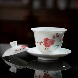 Red Blossom Gaiwan with lid removed, resting on a reflective black surface to highlight its translucent porcelain and hand-painted plum blossom design