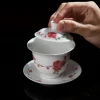 Lifting the lid of a Mei Leaf Gaiwan to reveal its smooth white interior, adorned with vibrant red blossom and bamboo motifs on the exterior