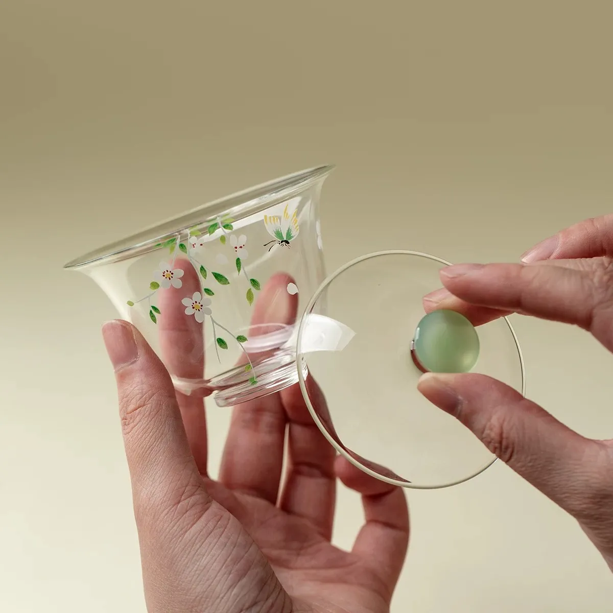 Made of Borosilicate Glass Gaiwan 95ml 4 Gaiwan Made of Borosilicate Glass held in hand, with lid separated to display its transparent body, hand-painted details, and jade-like lid knob.