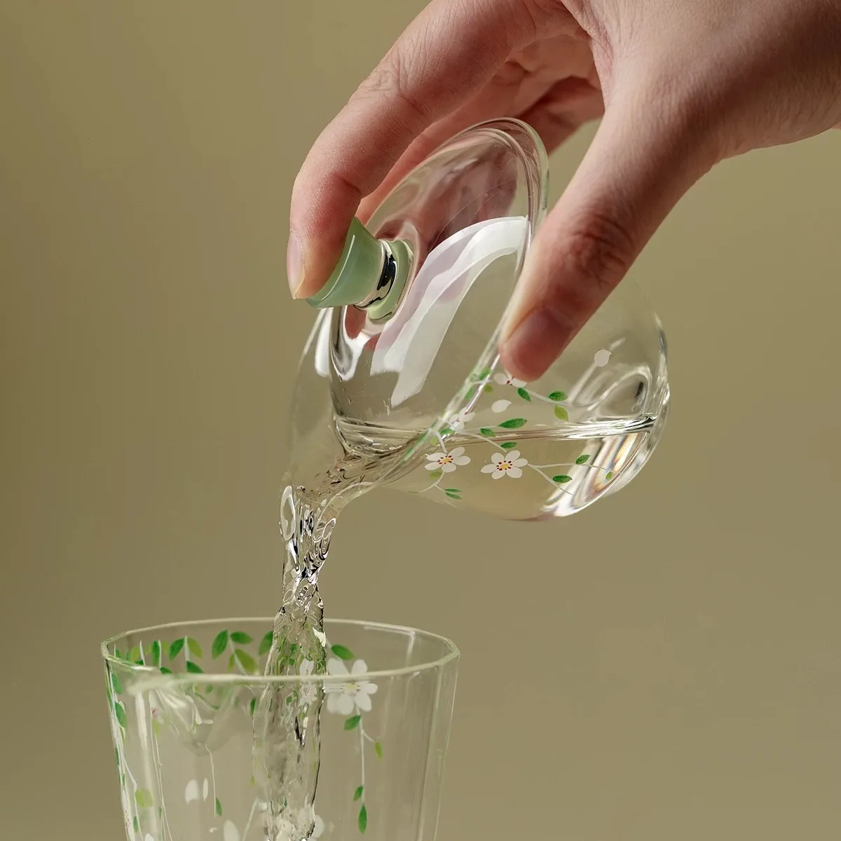 Made of Borosilicate Glass Gaiwan 95ml 5 Pouring tea from a Gaiwan Made of Borosilicate Glass into a matching glass teacup, highlighting its heat-resistant borosilicate material and smooth pouring design.