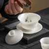 Adding tea leaves to a Mutton Fat Jade Gaiwan, capturing the traditional Kung Fu tea preparation ritual with this refined gaiwan tea bowl.