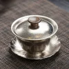 Titanium Gaiwan with lid on a lotus leaf saucer, placed on a woven tea mat, blending modern durability with traditional tea aesthetics.