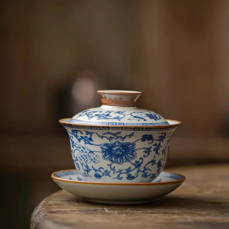 Traditional Blue and White Ru Kiln Gaiwan Tea Set 140 ml 1 Close-up of a Ruyao Gaiwan, a key piece of a Traditional Gaiwan Tea Set, with intricate blue floral underglaze patterns and a warm brown rim.