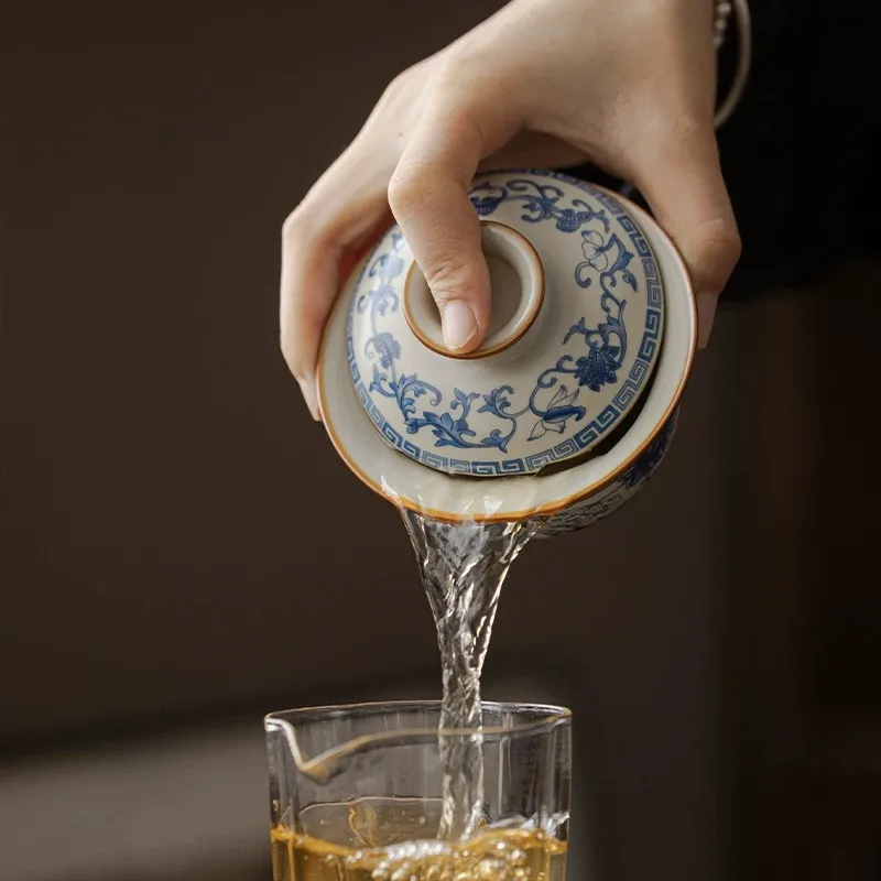 Traditional Blue and White Ru Kiln Gaiwan Tea Set 140 ml 4 Pouring tea from a Ruyao Gaiwan into a glass pitcher, showcasing the smooth pouring function of this Traditional Gaiwan Tea Set during a tea ceremony.