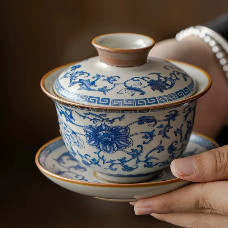 Traditional Blue and White Ru Kiln Gaiwan Tea Set 140 ml 5 Holding a complete Ruyao Gaiwan from a Traditional Gaiwan Tea Set, highlighting its delicate blue floral patterns and classic three-piece design.