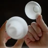 Mini Gaiwan, 50ml Gaiwan: White porcelain gaiwan with lid removed, held in hands to reveal its smooth interior
