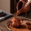 Warming a Yixing Pumpkin Purple Sand Teapot by pouring hot water over it, a traditional tea preparation step.