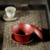 Yixing Purple Clay Gaiwan set with lid off on woven tea mat and a teacup in background for Gongfu tea