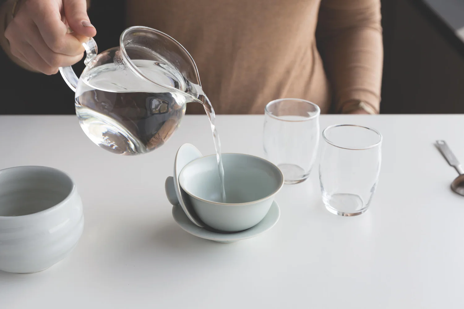 Step 1 of the gaiwan brewing guide: pouring hot water to warm a porcelain gaiwan for gaiwan tea preparation