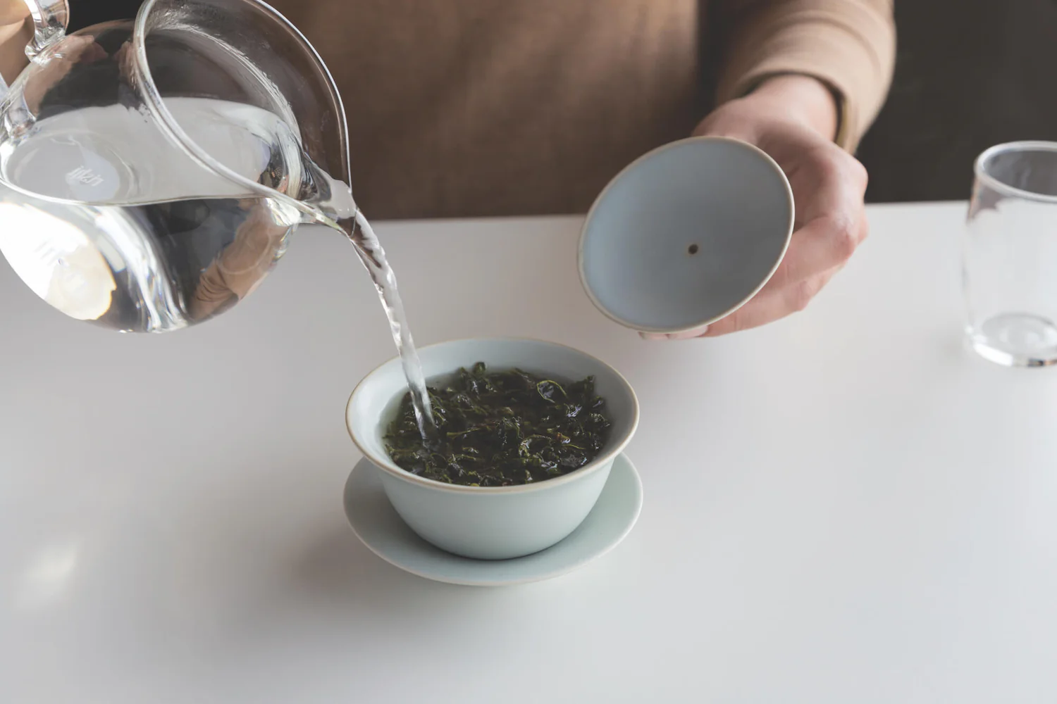 Gaiwan brewing step 3: pouring hot water along the inner wall of a gaiwan to steep loose tea leaves