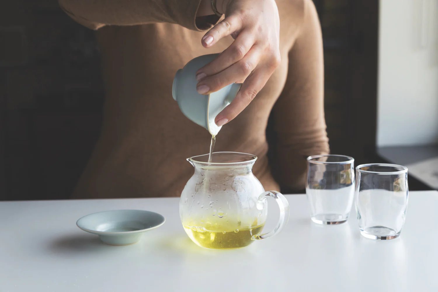 Step 5 of how to use a gaiwan: pouring freshly brewed gaiwan tea from the gaiwan into a glass fairness pitcher